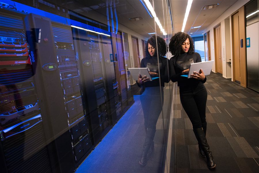 A technician checks a tablet beside a row of server racks